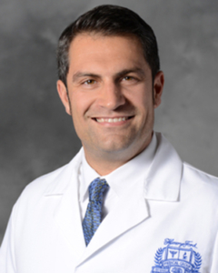 A photo of a man with a blue tie in a white lab coat