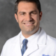 A photo of a man with a blue tie in a white lab coat