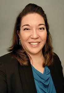 A head and shoulders photo of a woman with a grey background