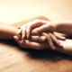 A photo of hands, one person holding another person's hand with both of their hands