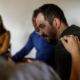 A woman's hand on a man's shoulder during a group therapy session