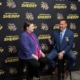 A man and woman talking in front of a backdrop that says "Genesee County Sheriff"